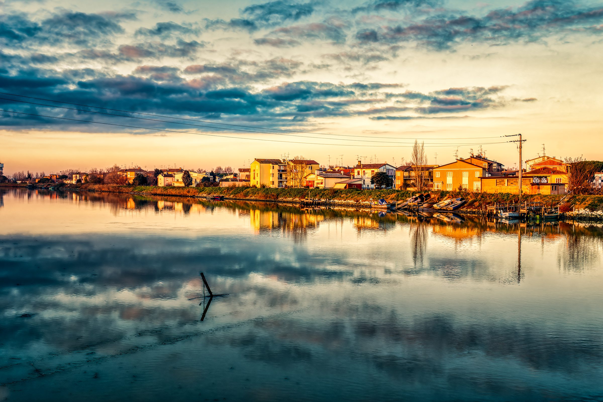 Sunset Magic: Driving Through the Valli di Comacchio Wetlands 9 Colorful houses of Comacchio reflected in still canal waters at golden hour