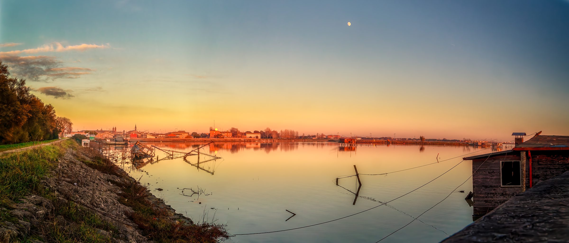 Sunset Magic: Driving Through the Valli di Comacchio Wetlands 12 Fishing huts silhouetted against golden sunset with moon rising over Valli di Comacchio