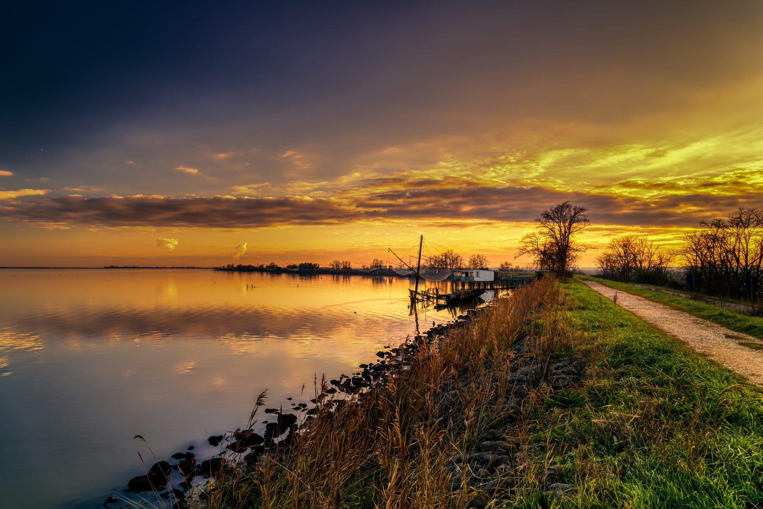 Sunset Magic: Driving Through the Valli di Comacchio Wetlands 5 Twilight gradient from sapphire to gold over Valli di Comacchio with traditional fishing structures
