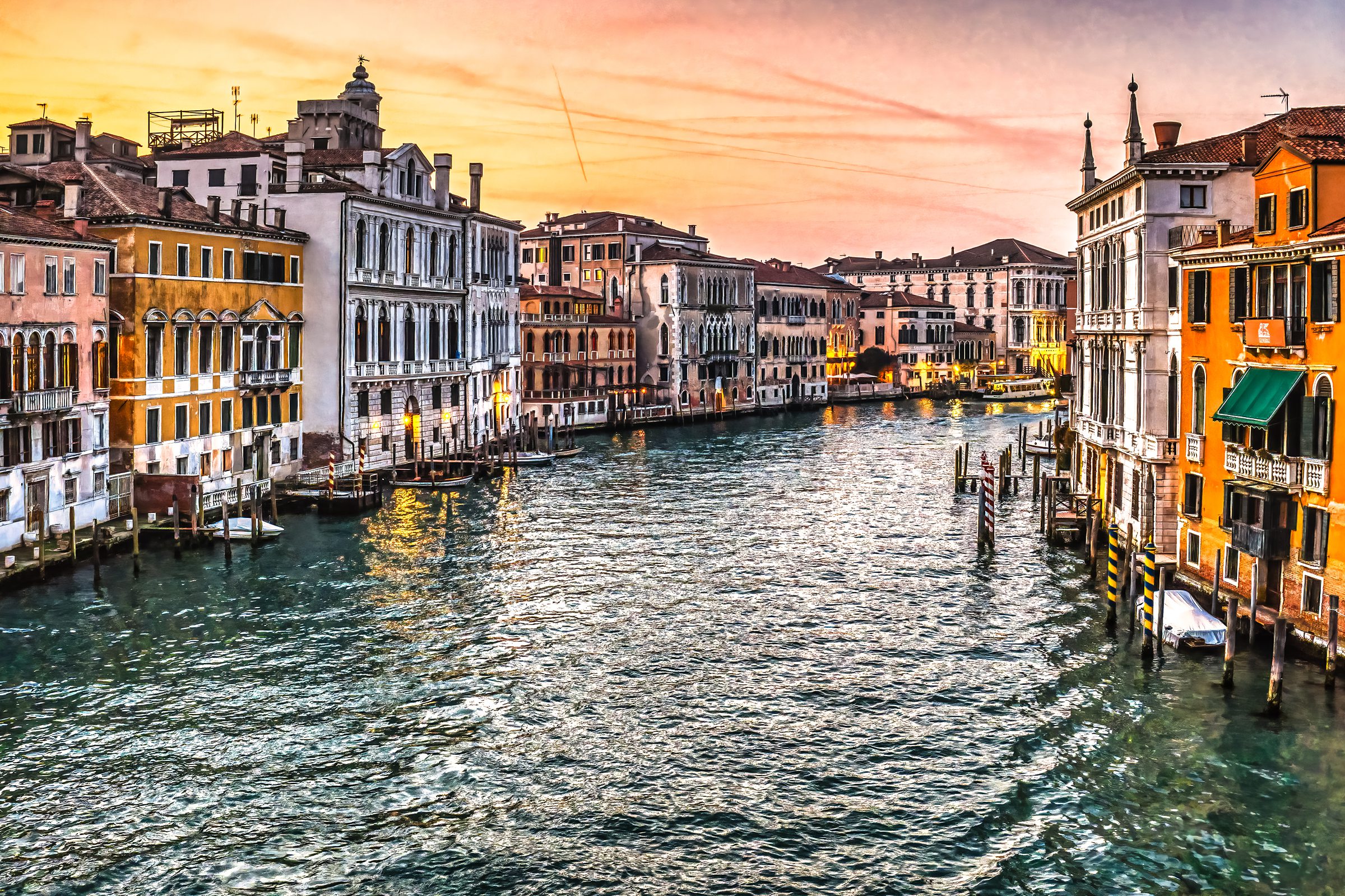 Venice Grand Canal at golden sunset with historic Venetian palaces reflecting warm light on the water